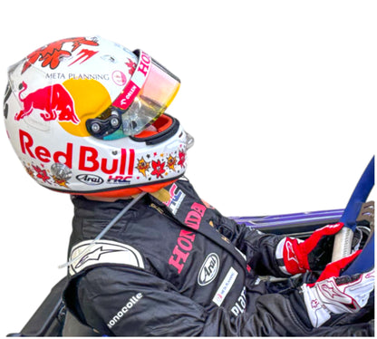 Racing driver in a car with a Red Bull helmet and suit