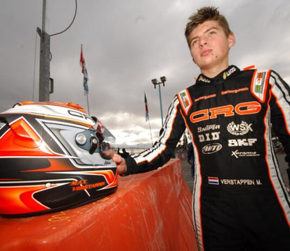 Person in racing suit with helmet on a podium at a race track